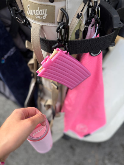 GTee-Magz pink golf tee dispenser attached to golf bag, sleek magazine-style holder for tees, stylish golf accessory for women golfers.